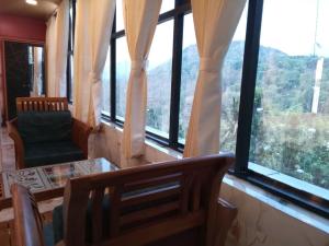 a room with a table and chairs and windows at Majestic Marvel in Maraiyūr