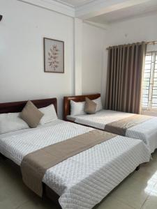 two beds in a white room with a window at An Phú Stay & Coffee in Cửa Lô
