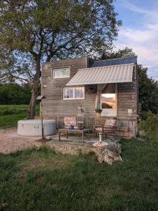a tiny house with a bench and a table at Tiny chouette et jacuzzi in Doulezon