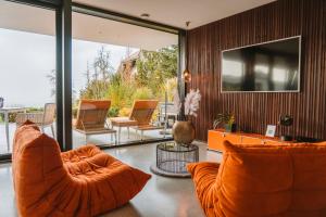 a living room with orange chairs and a television at ORANGE LOUNGE Attersee in Weyregg