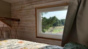 a bedroom with a window in a wooden wall at Tiny chouette et jacuzzi in Doulezon