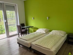 two beds in a room with a green wall at Tisza Garden Park in Tiszalök