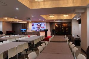 a conference room with tables and chairs and a screen at Art Five Hotel BOIS博多 in Fukuoka