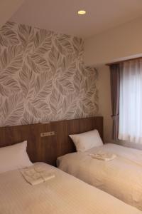 two beds in a hotel room with a wall mural at Art Five Hotel BOIS博多 in Fukuoka