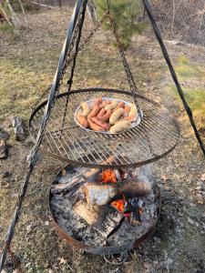 a grill with a bunch of hot dogs and a fire at Bolek i Lolek domki do wynajęcia in Popielżyn Dolny