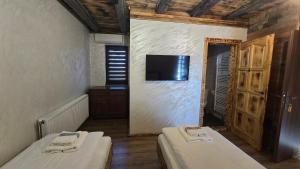 two beds in a room with a tv on the wall at La Hotar in Buchin