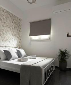a white bedroom with a bed with a window at Margarita in Chania