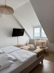 a white bedroom with a bed and a chair at Enklawa - Floryn Mielno in Mielno