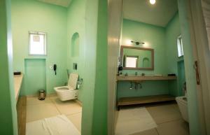 a green bathroom with a toilet and a sink at Kadamb Bagh-A Luxury Nature Resort Sariska in Rāmsinghpura +29 photos