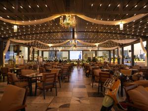 a restaurant with tables and chairs and a chandelier at Babylon Rotana Hotel in Baghdād