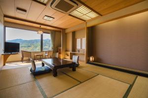 ein Wohnzimmer mit einem Tisch und einem großen Fenster in der Unterkunft Hotel Ryutouen in Saga