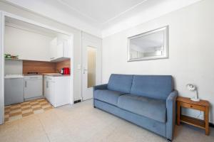 a living room with a blue couch and a kitchen at LE FELIX FAURE - Hyper Centre - Terrasse - Plages in Menton