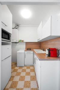 a kitchen with white cabinets and a red appliance at LE FELIX FAURE - Hyper Centre - Terrasse - Plages in Menton