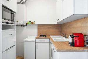 a kitchen with white cabinets and a red appliance at LE FELIX FAURE - Hyper Centre - Terrasse - Plages in Menton