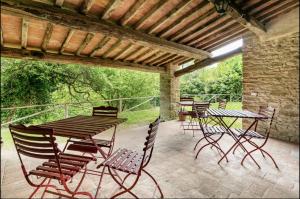 a patio with tables and chairs under a wooden roof at Villa Toscanna in Pelago