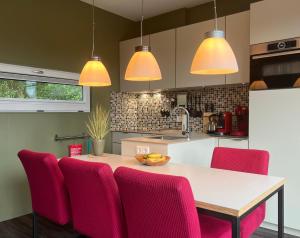 a kitchen with pink chairs and a white table at Anpektop - Ecohuisjes Terschelling in Midsland +16 photos
