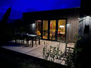 a deck with chairs and a table at night at Anpektop - Ecohuisjes Terschelling in Midsland