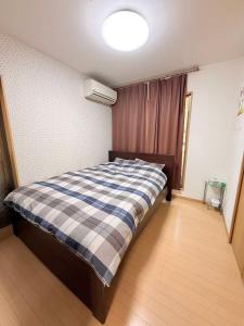 a bedroom with a bed with a plaid blanket at 十五夜 in Osaka
