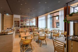 a restaurant with wooden tables and chairs and windows at IntercityHotel Herford in Herford