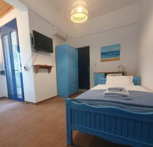 a bedroom with a blue bed and a tv at Babis & Popi Rooms and Studios in Frangokastello