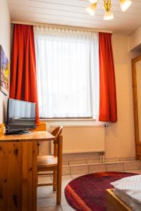 a room with a desk with a television and a window at Hotel Garni Zielinski in Sindelfingen