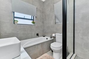 a bathroom with a toilet and a tub and a sink at Chanty Serenity- workstation, gym, backup power &Pool in Sandton