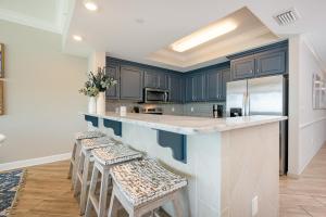a kitchen with blue cabinets and a counter with stools at Phoenix Orange Beach II 2103 in Orange Beach