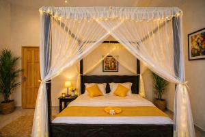 a bedroom with a canopy bed with yellow pillows at Kaliba Beach - Rutsiro in Rutsiro +24 photos