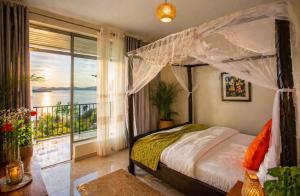 a bedroom with a canopy bed and a balcony at Kaliba Beach - Rutsiro in Rutsiro