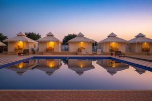a villa with a pool at night with huts at Sunrise Resort Jaislamer in Jaisalmer