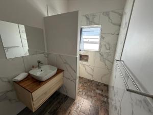 a white bathroom with a sink and a mirror at Berg & Baai guesthouse in Plettenberg Bay