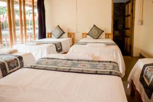 three beds in a room with windows at Bong Bang homestay 2 in Na Hang