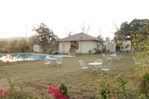 a group of chairs and tables in a yard with a pool at Tuli Orchid - A Boutique Eco Resort in Rāmtek