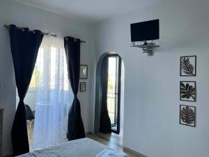 a bedroom with a bed and a window with a television at Vesper Rooms in Skala Prinou