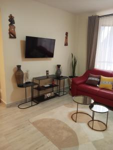 a living room with a red couch and a flat screen tv at Kwame Homes in Nakuru