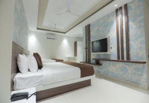 a hotel room with a bed and a television at Nandha Grande in Udumalaippettai