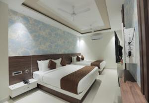 a bedroom with two beds in a room with a painting at Nandha Grande in Udumalaippettai