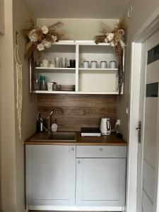 a kitchen with white cabinets and a sink at Apartament Boho Monte 60 in Sopot