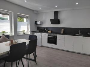 a kitchen with white cabinets and a table and chairs at The Günz Homes 2 in Günzburg