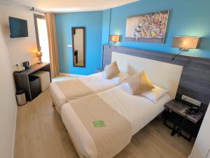 a bedroom with a large bed with blue walls at Hôtel Le Collier in Antibes