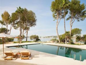 a swimming pool with two chairs and palm trees at Mandarin Oriental Punta Negra, Mallorca in Palmanova