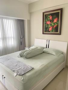a bed in a bedroom with a painting on the wall at Springlake apartment b in Rawabugel