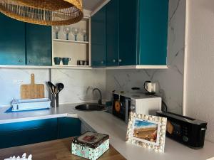 a kitchen with blue cabinets and a microwave on a counter at Perlazul in Peniscola