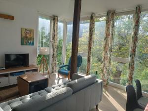 a living room with a couch and chairs and windows at O Salgueiral in Castro Caldelas