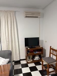 a living room with a television and a checkered floor at Casa en la Huertecilla in Lora del Río