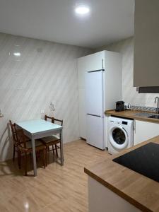 a kitchen with a table and a white refrigerator at Casa en la Huertecilla in Lora del Río +9 photos