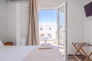 a bedroom with a bed and a balcony with a table at Depis luxury private villas in Plaka +78 photos