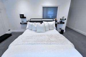 a large white bed with white pillows in a room at Central spacious town house in Exeter