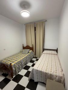 two beds in a room with a checkered floor at Casa en la Huertecilla in Lora del Río