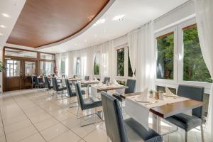 ein Restaurant mit Tischen, Stühlen und Fenstern in der Unterkunft Hotel ANTARES in Bratislava